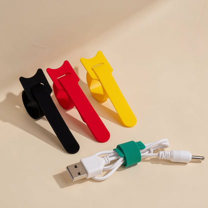 Black, red and yellow Colortie cable ties beside a white USB cable bundled with a green tie