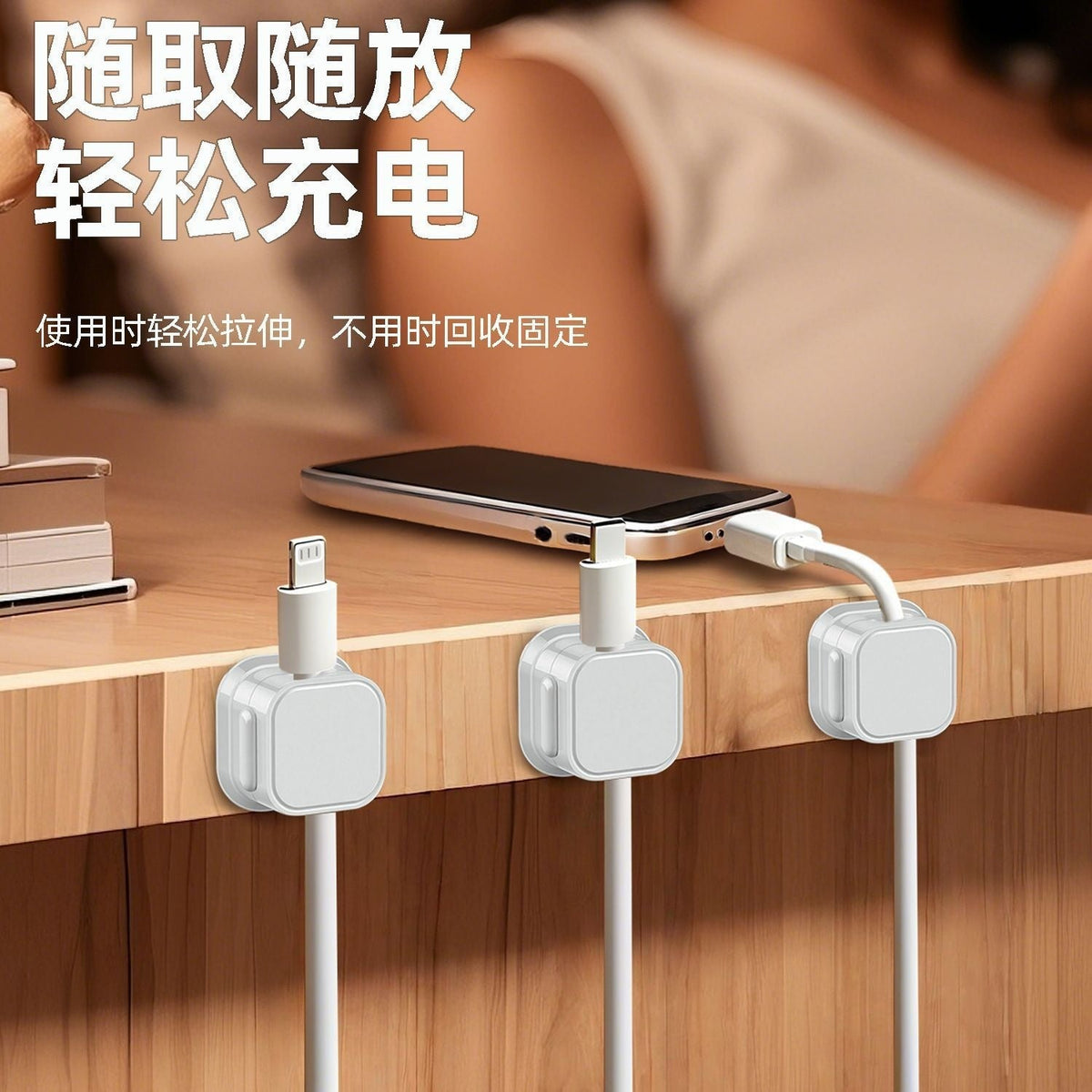 Magnetclip – Three white magnetic cable clips on a desk edge holding charging cables beside a phone lying on the desk