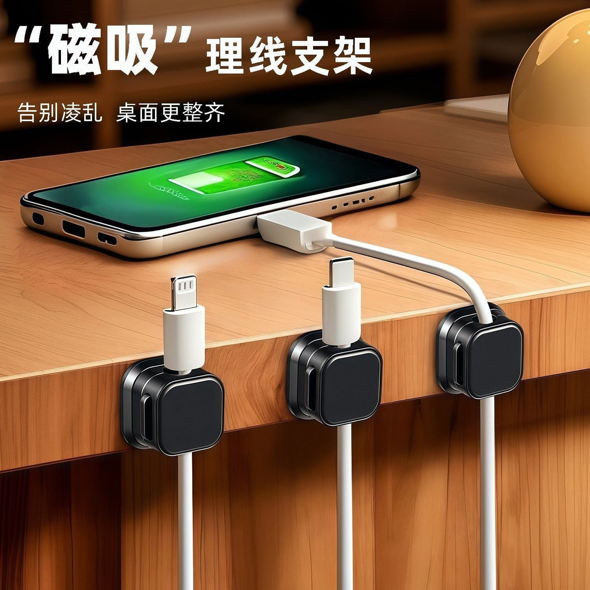 Magnetclip – Three black magnetic cable clips on a wooden desk edge with a charging phone and white cables routed through