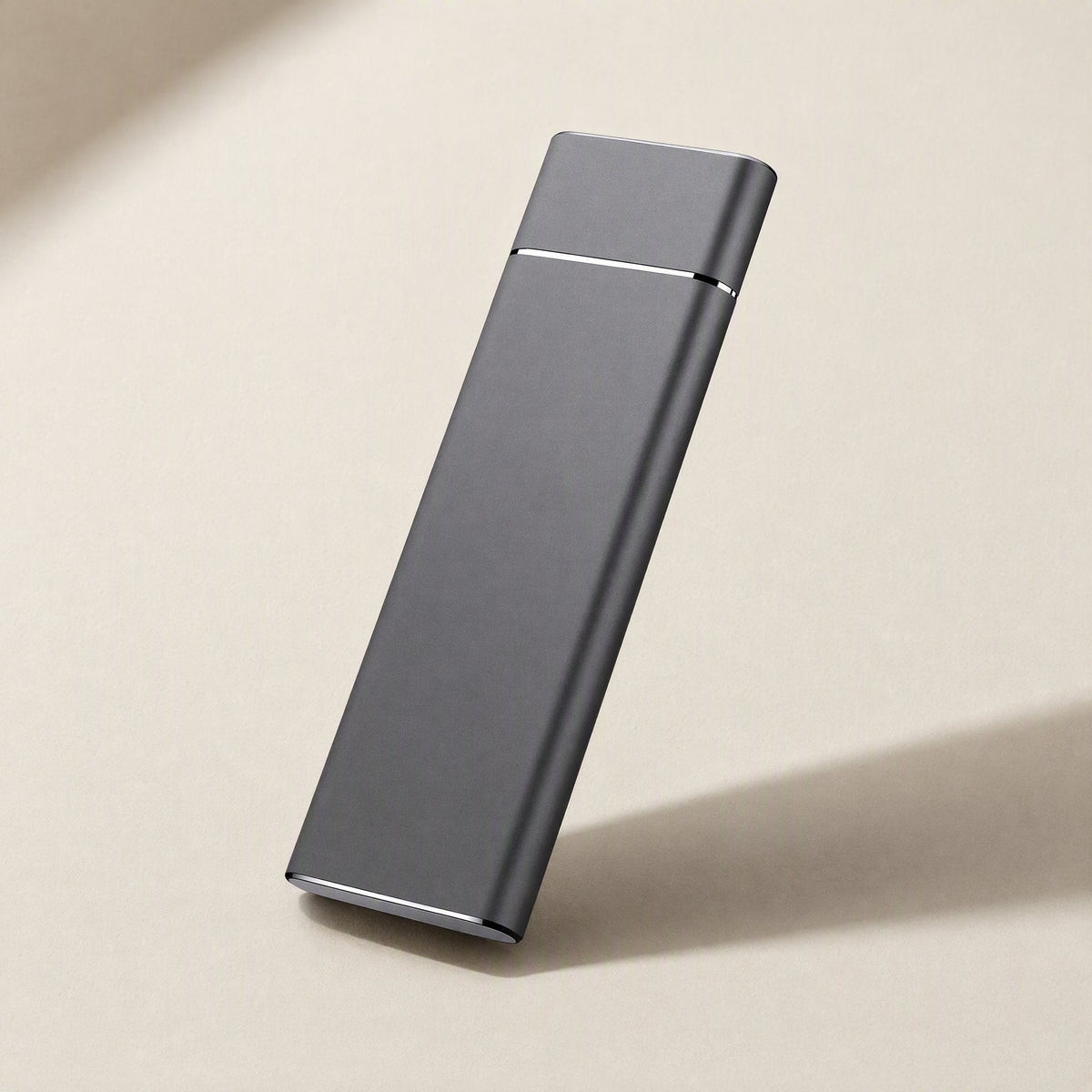 Driveglide – Slim dark gray metal drive standing at an angle on a beige surface with a soft shadow