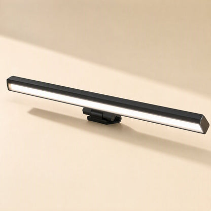 Screenlamp – Black rectangular monitor light bar with a hinged clip, shown from a front angle with its glowing diffuser lit