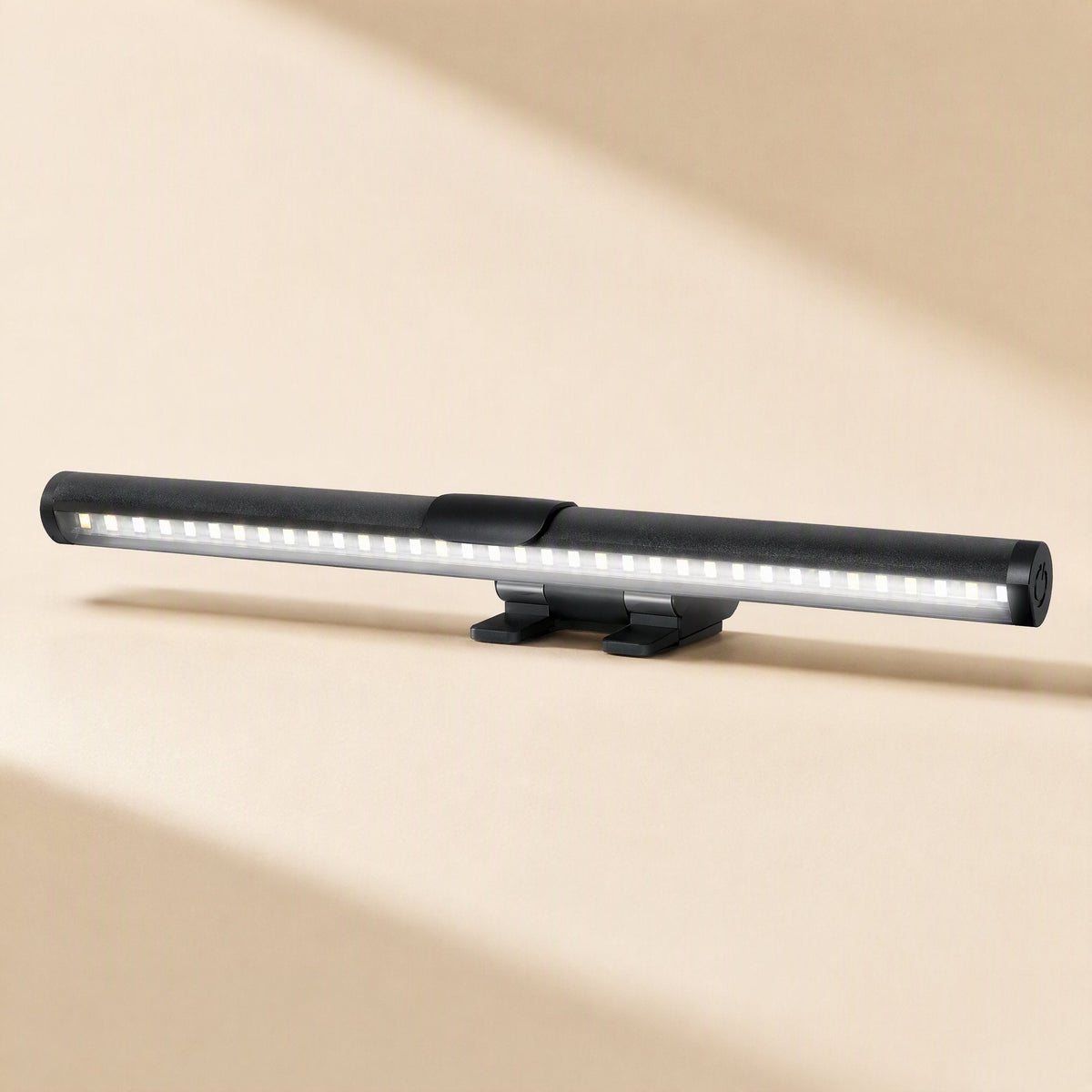Screenlamp – Cylindrical black light bar with visible rows of small LEDs and a dual-leg clip base on a beige surface