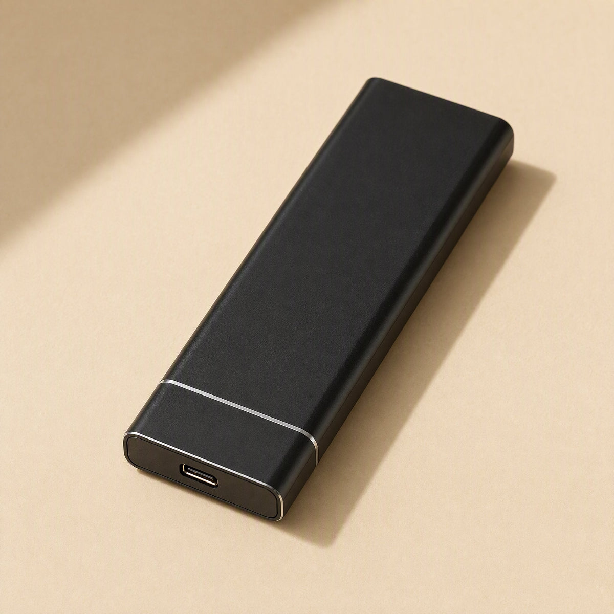 Drivevault – Black metal portable solid state drive with a USB-C port at one end on a beige surface