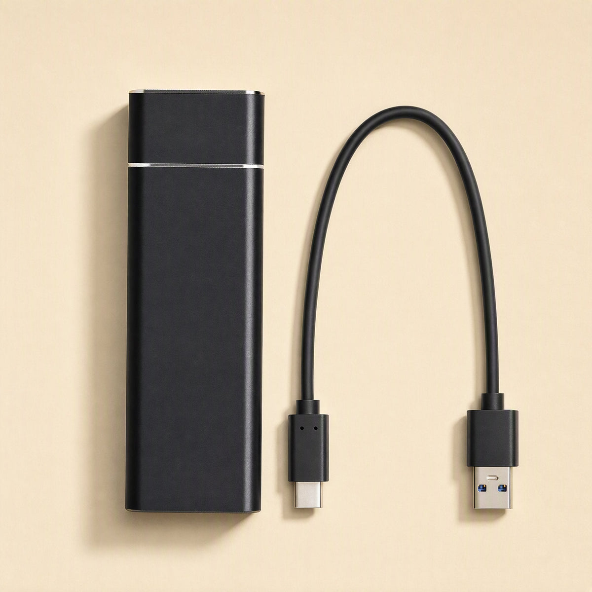 Drivevault – Black portable drive beside a detachable USB-C to USB-A cable on a beige background