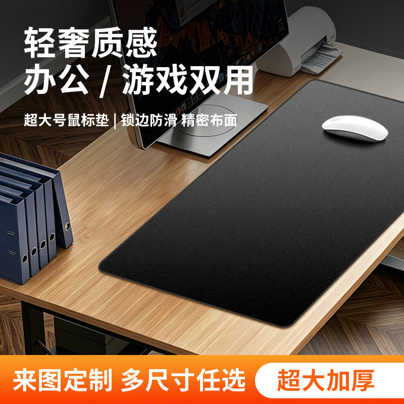 Dapple Desk Mat in black on a wooden desk beside a monitor, with a white mouse resting on top