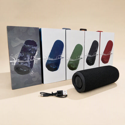 Splashbeat – Black speaker in front of five boxes in camo, blue, green, black and red, with a charging cable