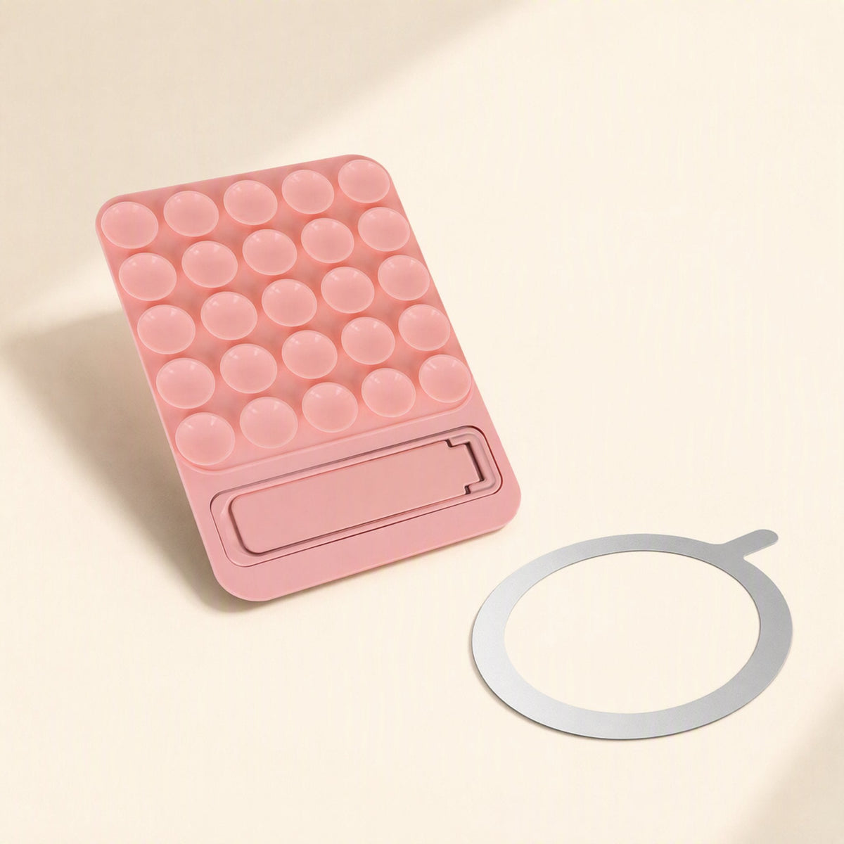 Suctionnest – Pink suction cup holder with kickstand at the bottom, next to a round metal magnetic ring