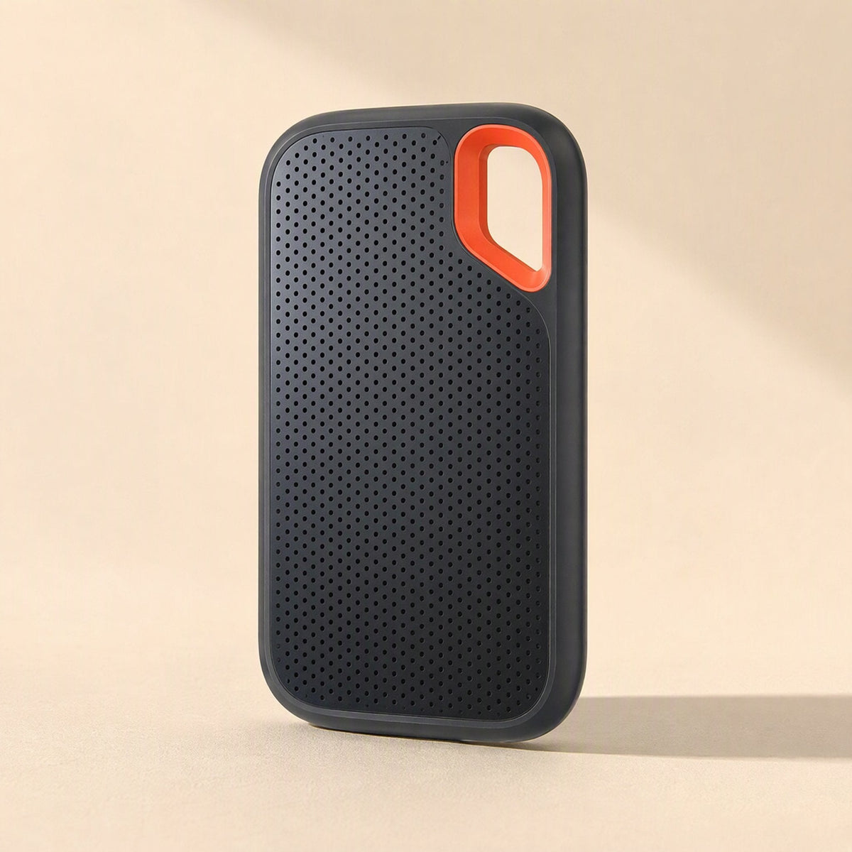 Roamdisk Solid-State Mobile Hard Drive standing upright, showing perforated black front and orange loop corner