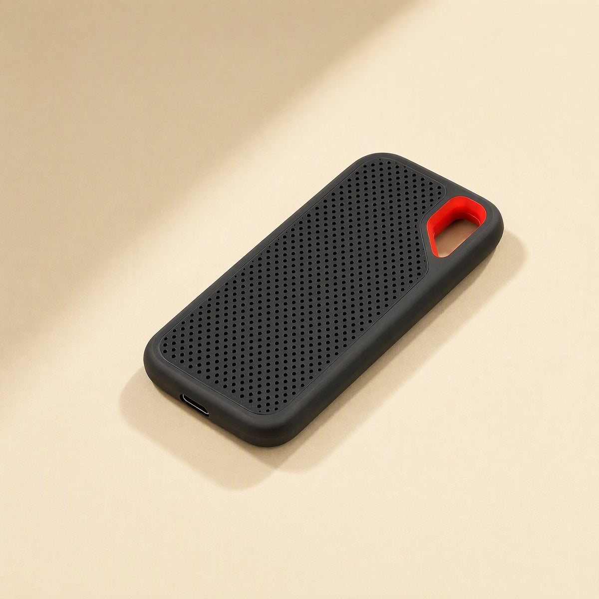 Roamdisk – Black drive lying flat on a cream surface, with orange loop and USB-C port visible at the bottom edge