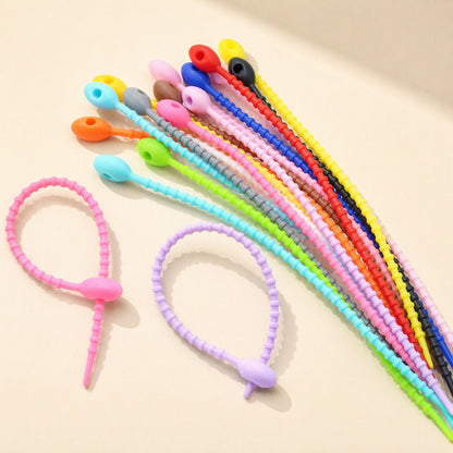 Cordtame Cable Organizer silicone ties in many colours fanned out, with two looped into rings in front