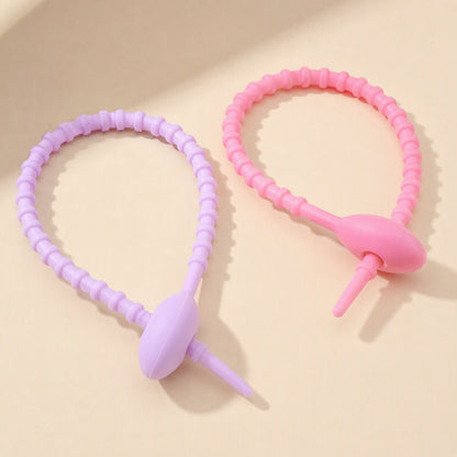 Cordtame Cable Organizer – pink and lilac silicone ties looped closed, tapered tips poking through their oval heads
