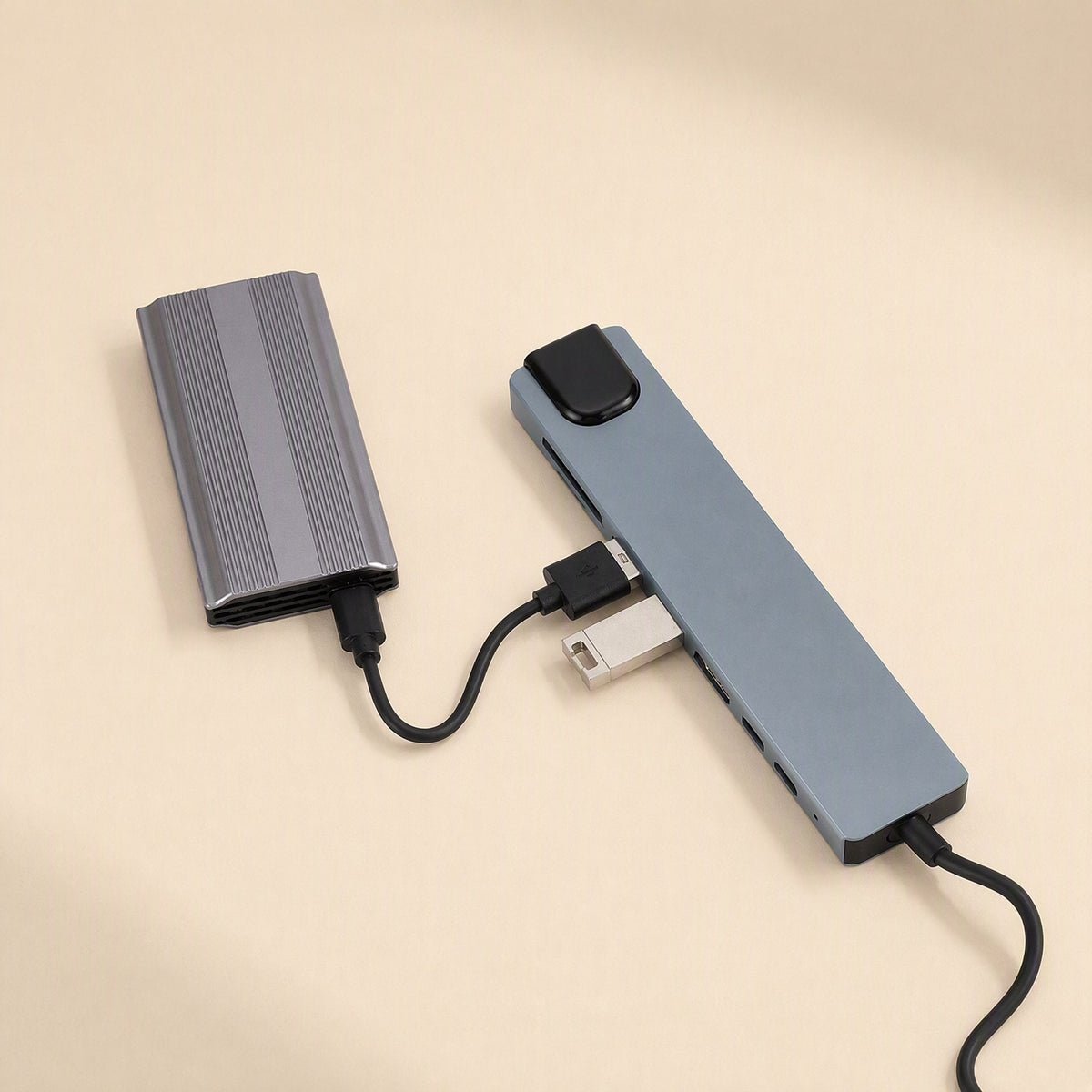 Portspan – Space gray docking station connected to an external drive and a USB flash drive on a beige surface