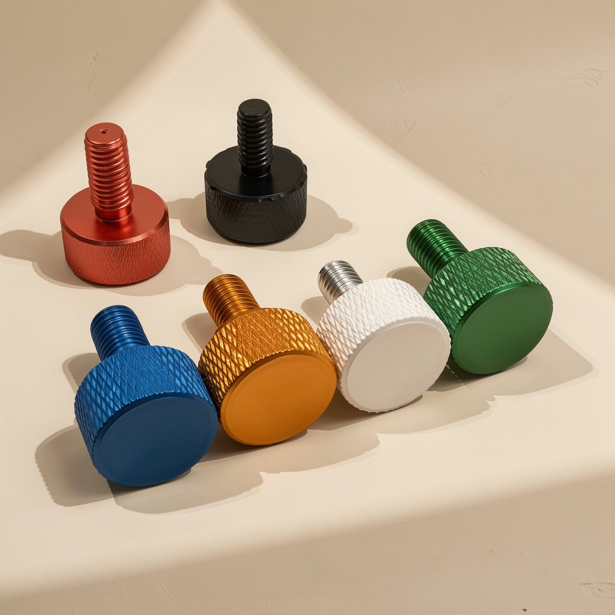 Caseclasp – Six knurled thumb screws in orange, black, blue, gold, white and green arranged on a cream surface