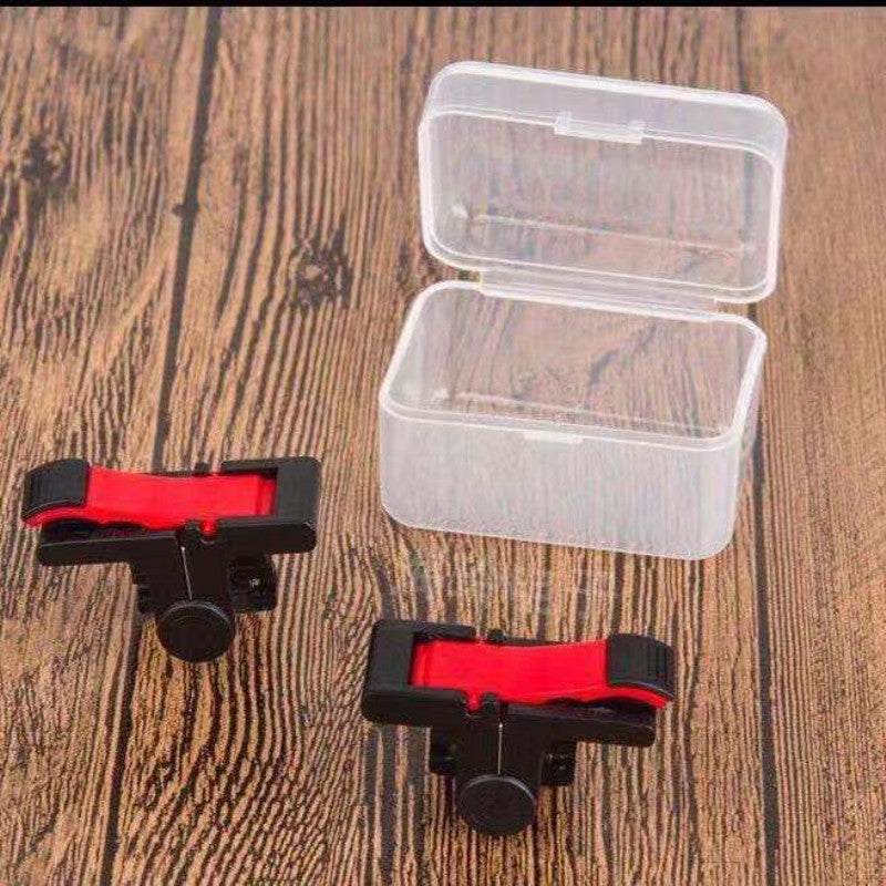 Pressplay Mobile Game Controller: pair of black and red trigger buttons beside a clear plastic case on wood