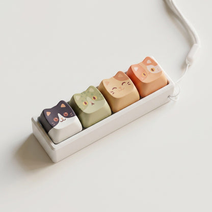 Furrkey – Row of four cat keycaps in a white holder with a looped white cord, seen from above on a plain white surface