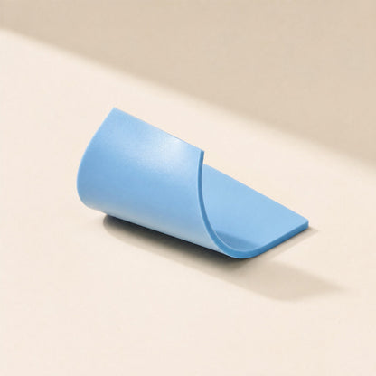 Thermaseal – Blue silicone pad curled into a roll on a cream background, showing its thickness and flexible edge
