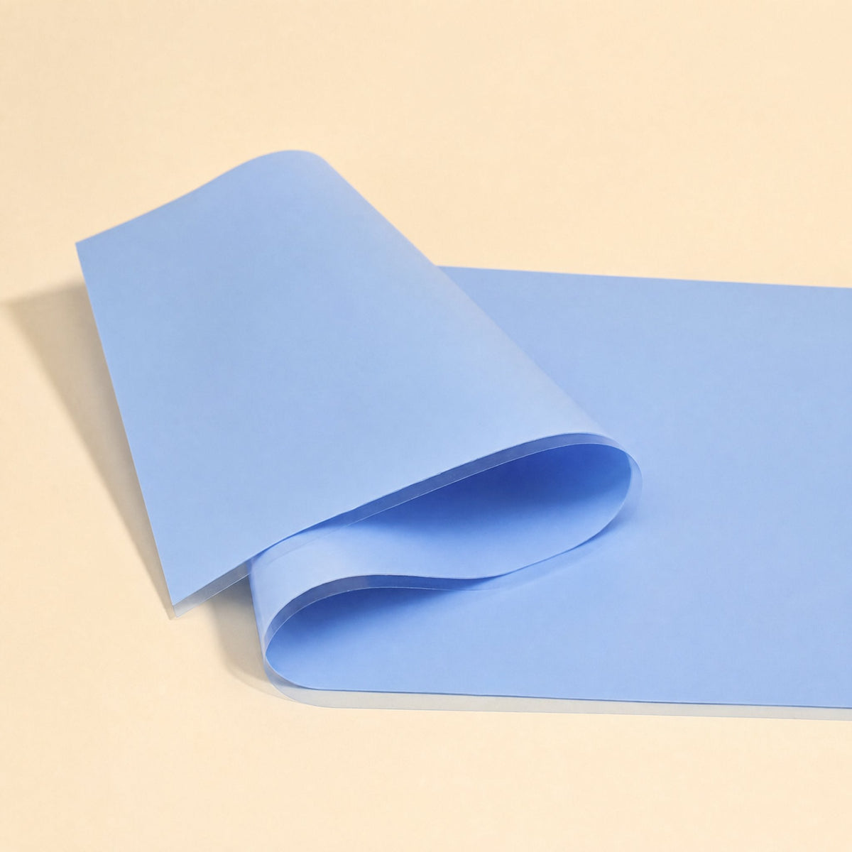Thermaseal – Large blue silicone sheet with a clear liner folded over at the corner on a cream background