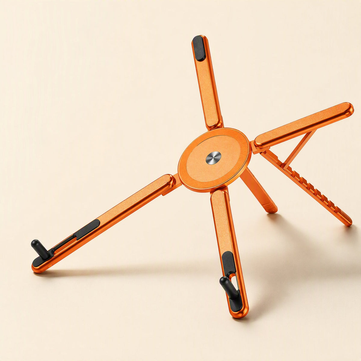 Magdesk – Top-down view of the orange stand with a matte magnetic center disc and one leg with notched adjustment slots