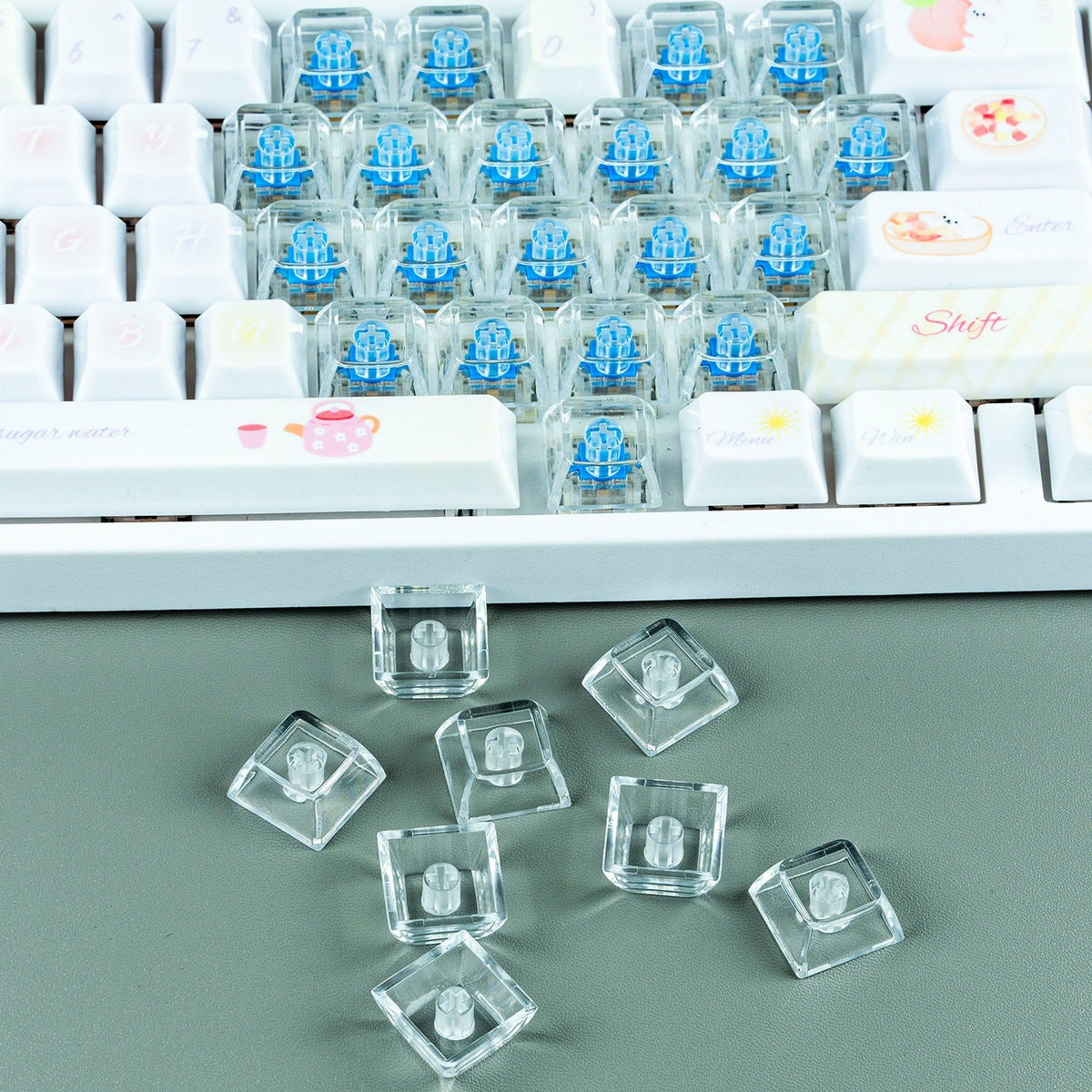 Clearcap – Clear keycaps with cross stems on a green desk in front of a white keyboard with blue switches showing through