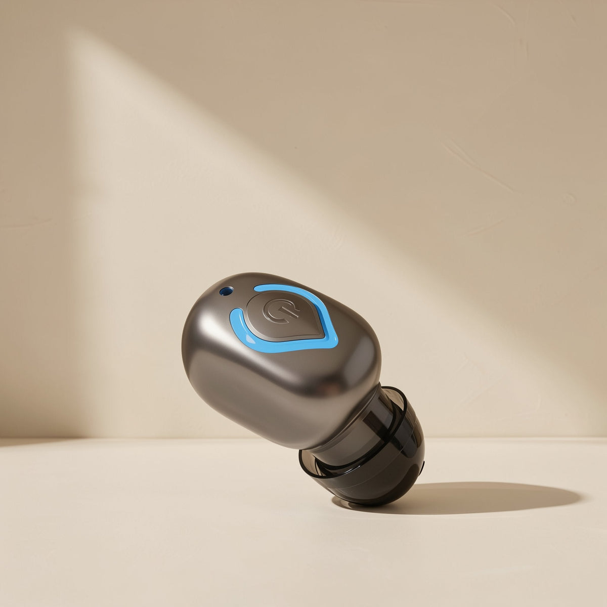 Solehear Single Ear Bluetooth Earbud in gunmetal gray with a blue power button, tilted on a cream surface