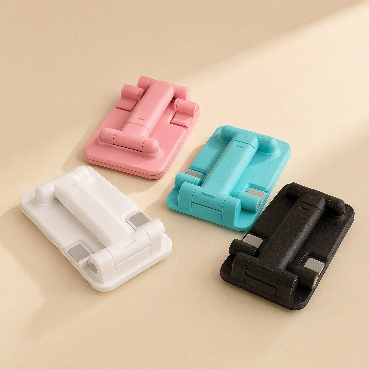 Flipangle – Top-down view of four folded stands in pink, teal, white and black, showing the hinged arms