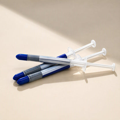 Heatbond Gray Thermal Paste Syringe, three blue-capped syringes piled on a cream surface