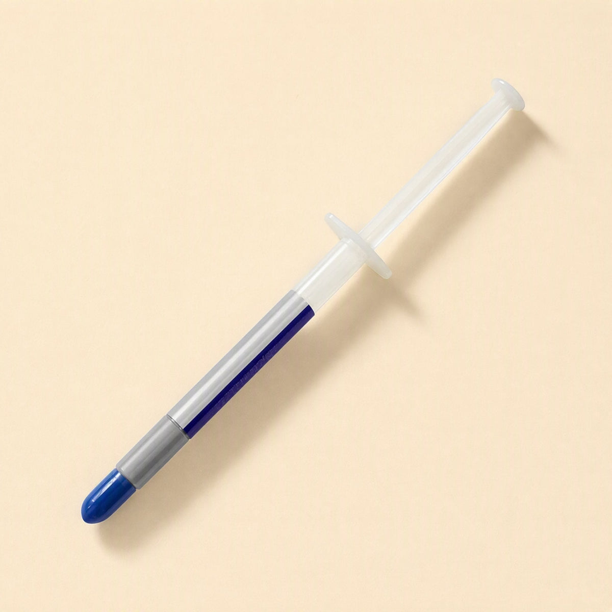 Heatbond – Syringe with clear barrel showing gray paste and a blue cap, viewed from above