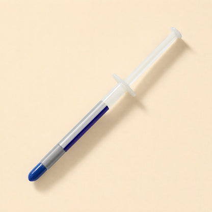 Heatbond – Syringe with clear barrel showing gray paste and a blue cap, viewed from above