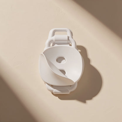 Deskclip – White cable clip with curved cover and two screw holes, seen from the front on a beige wall