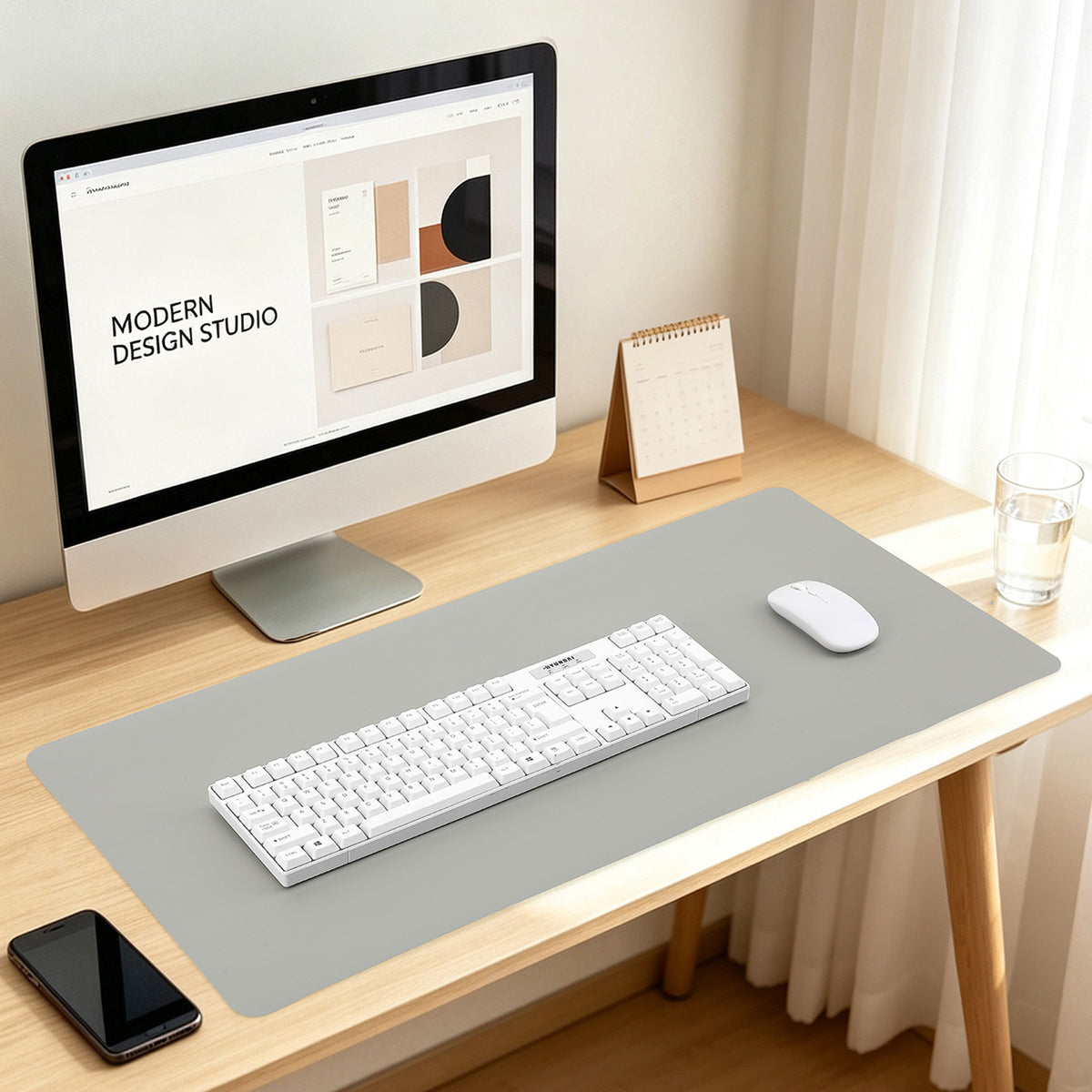 Dualhide – Grey desk mat on a wooden desk holding a white keyboard and mouse beside a monitor and phone