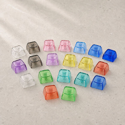 Clarion Blank PC Keycap in translucent clear, pink, purple, yellow, green, teal, blue and orange on a stone surface