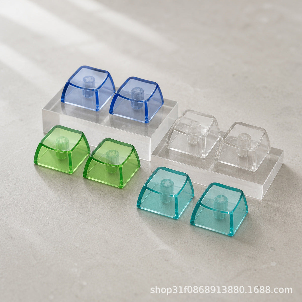 Clarion – Underside view of blue, green, teal and clear keycaps in pairs showing the stems, resting on clear acrylic blocks