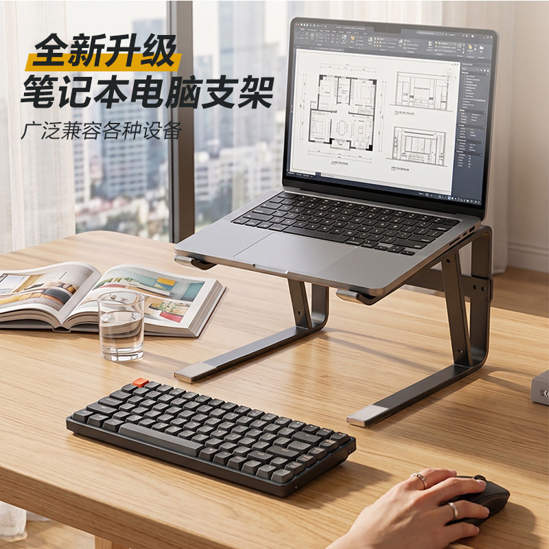 Loftvent laptop stand holding a laptop on a wooden desk beside a compact keyboard, glass of water and open magazine