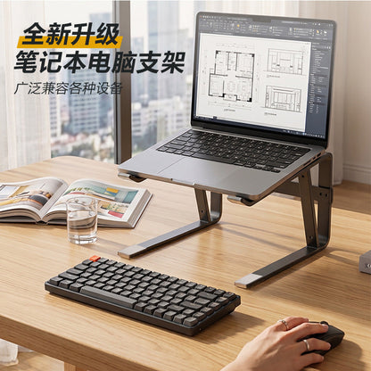 Loftvent laptop stand holding a laptop on a wooden desk beside a compact keyboard, glass of water and open magazine