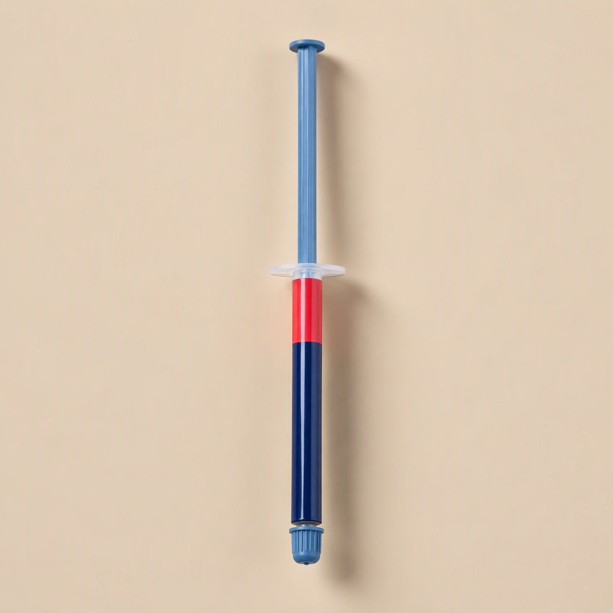 Chipglide CPU Thermal Paste – slim syringe with blue plunger, red band and navy barrel standing upright on a peach background