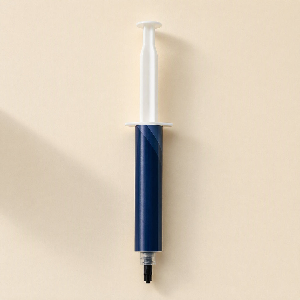 Chipglide – Wider-barrel navy syringe with white plunger and black tip cap, viewed from above on a beige surface