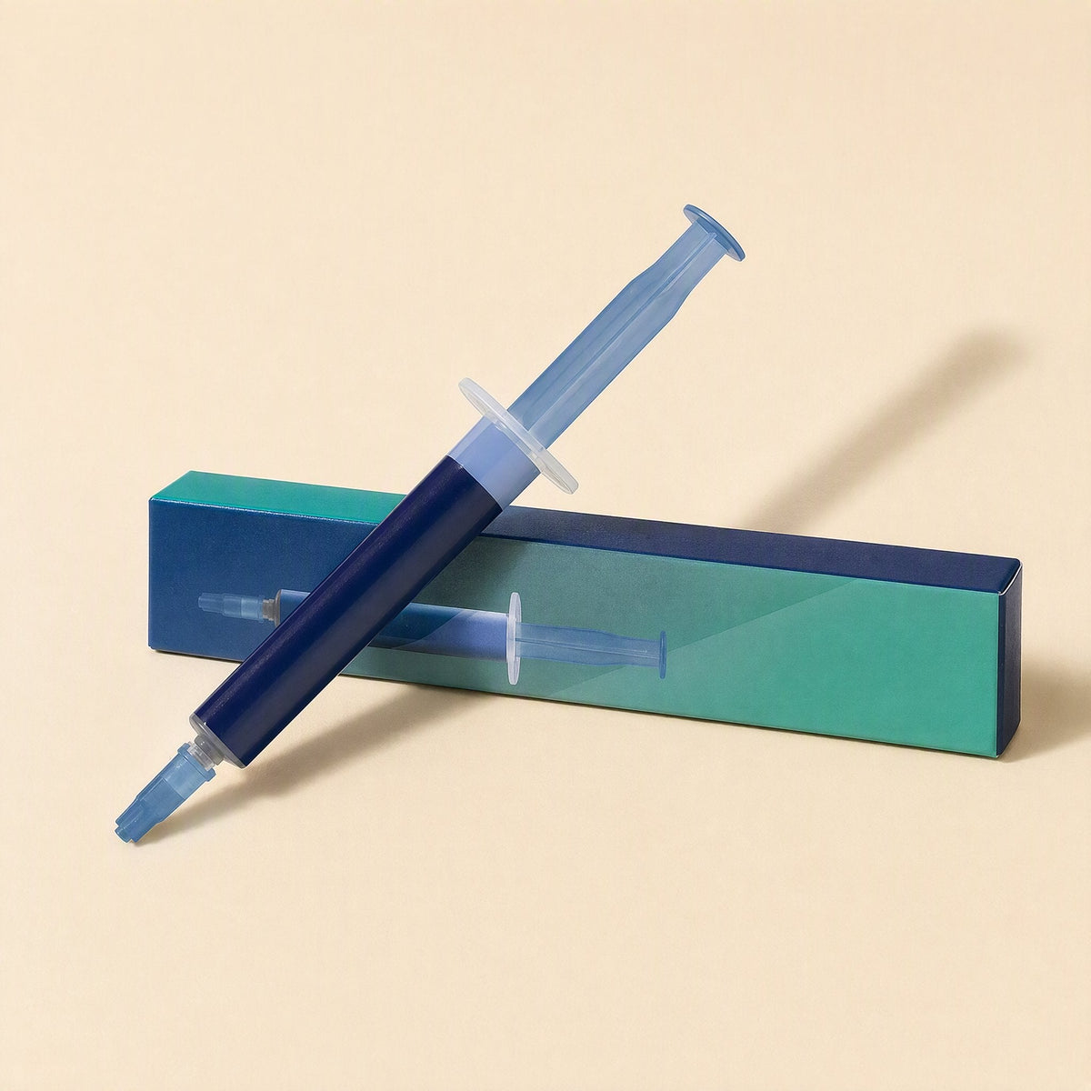 Chipglide CPU Thermal Paste – navy syringe with light blue plunger and tip leaning against a teal and blue box