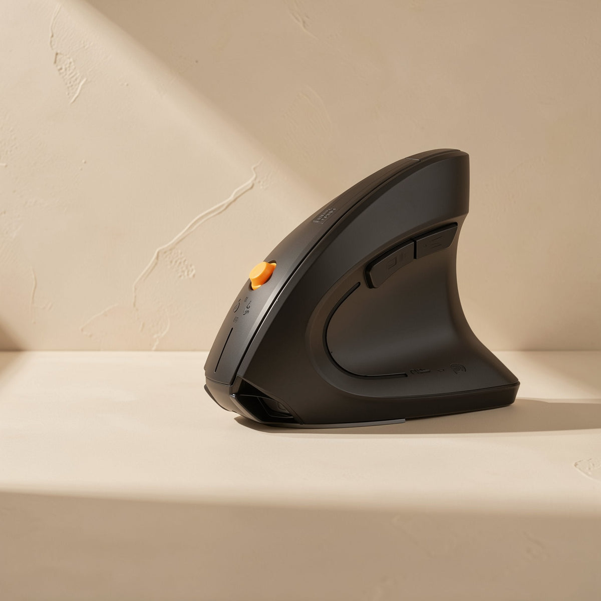 Palmglide M830 Wireless Ergonomic Mouse in black, side view with an orange scroll wheel on a beige surface