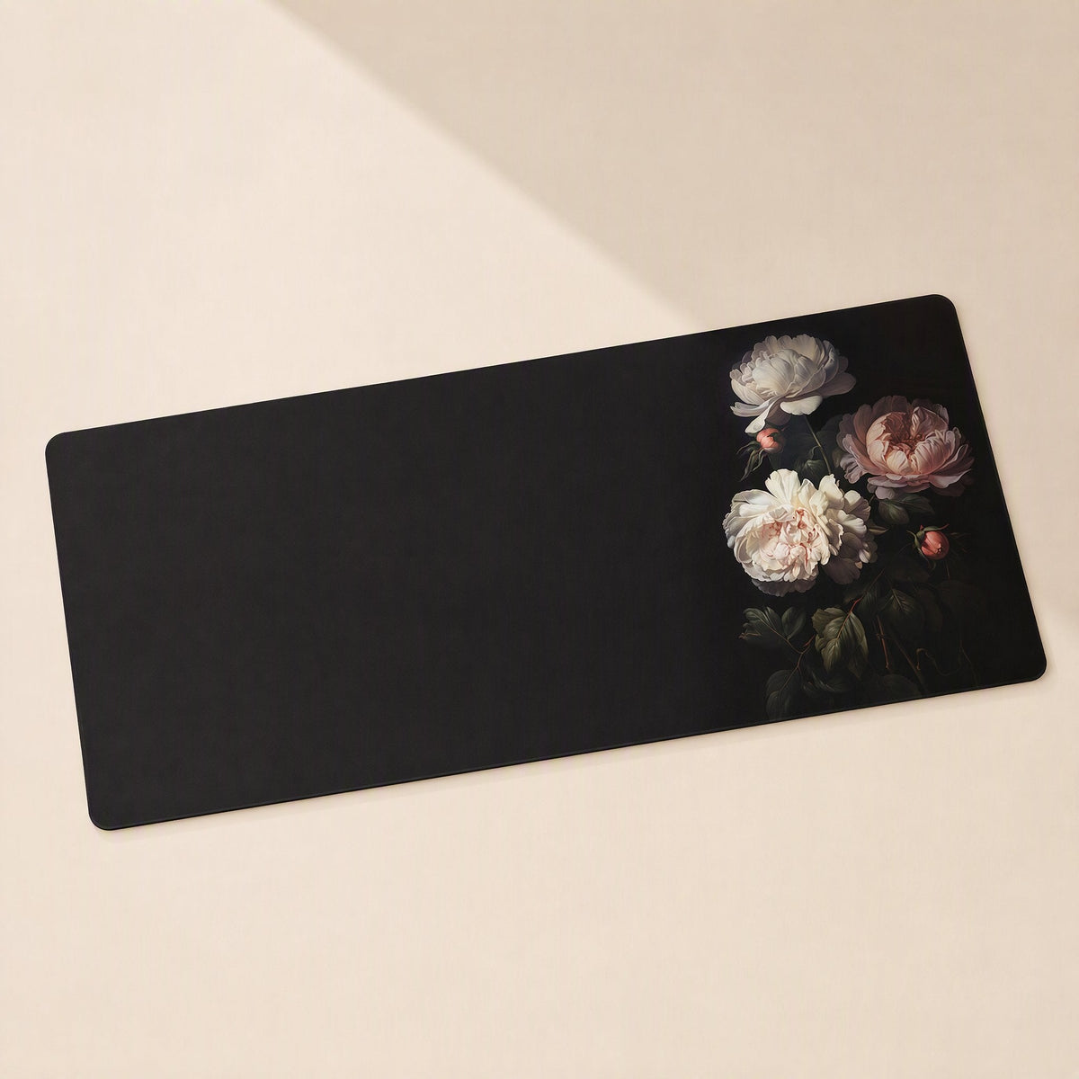 Gripdesk Rubber Desk Mat in black with pink and white peonies on the right, angled view on a cream surface