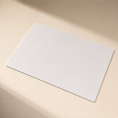 Gripdesk – Plain light grey rectangular desk mat lying flat at an angle with soft window shadows across it