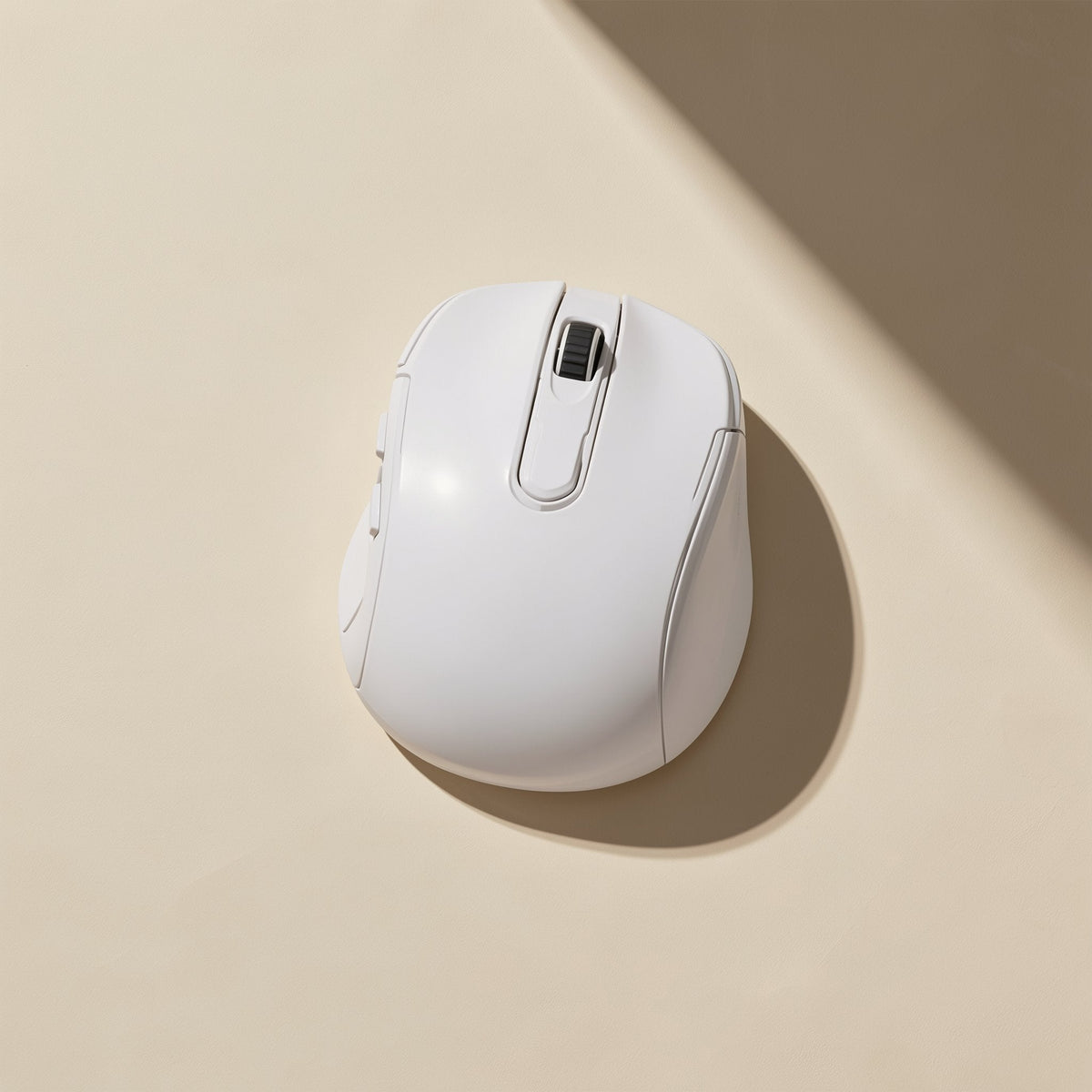 Glidebeam – White wireless mouse seen from above with scroll wheel and side grip, casting a shadow on a tan background
