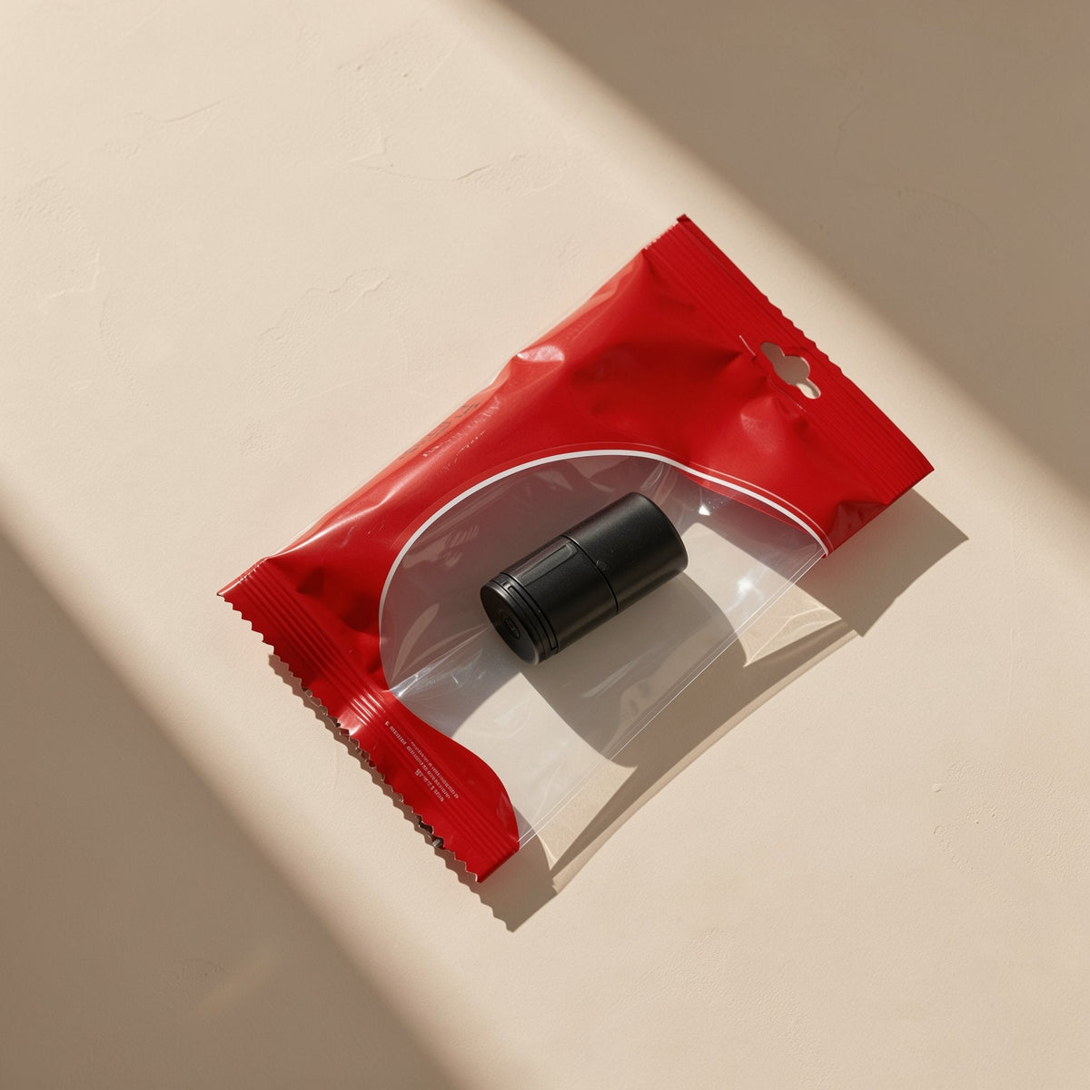 Cardport USB TF card reader, a small black cylinder, inside a red and clear zip pouch on a beige surface
