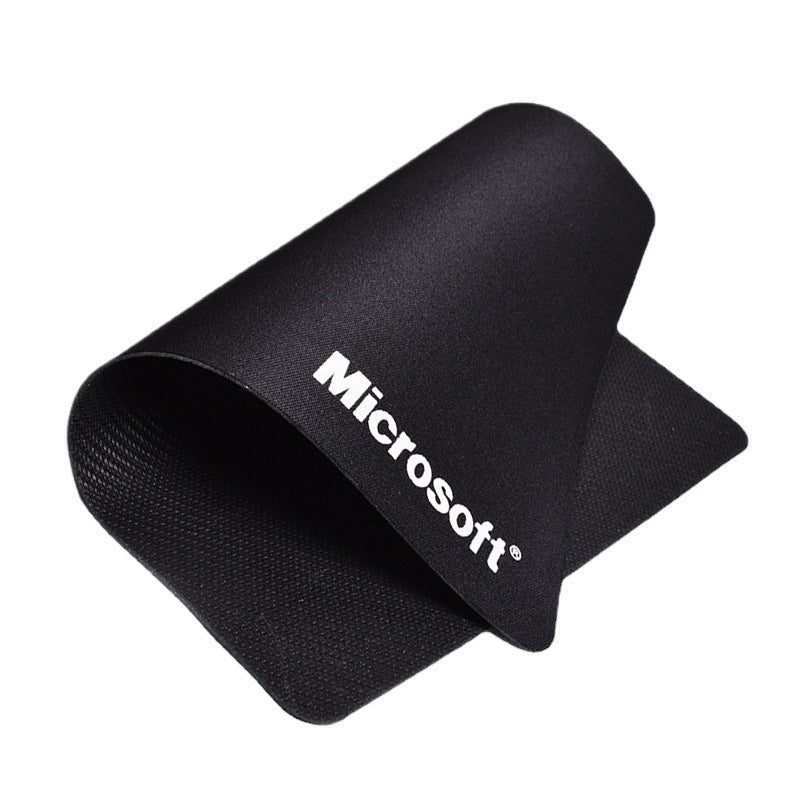 Weavepad – Black mouse pad curled up on a white background, white Microsoft logo and woven rubber underside visible
