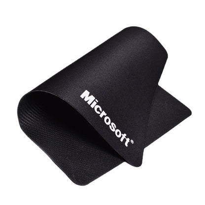 Weavepad – Black mouse pad curled up on a white background, white Microsoft logo and woven rubber underside visible