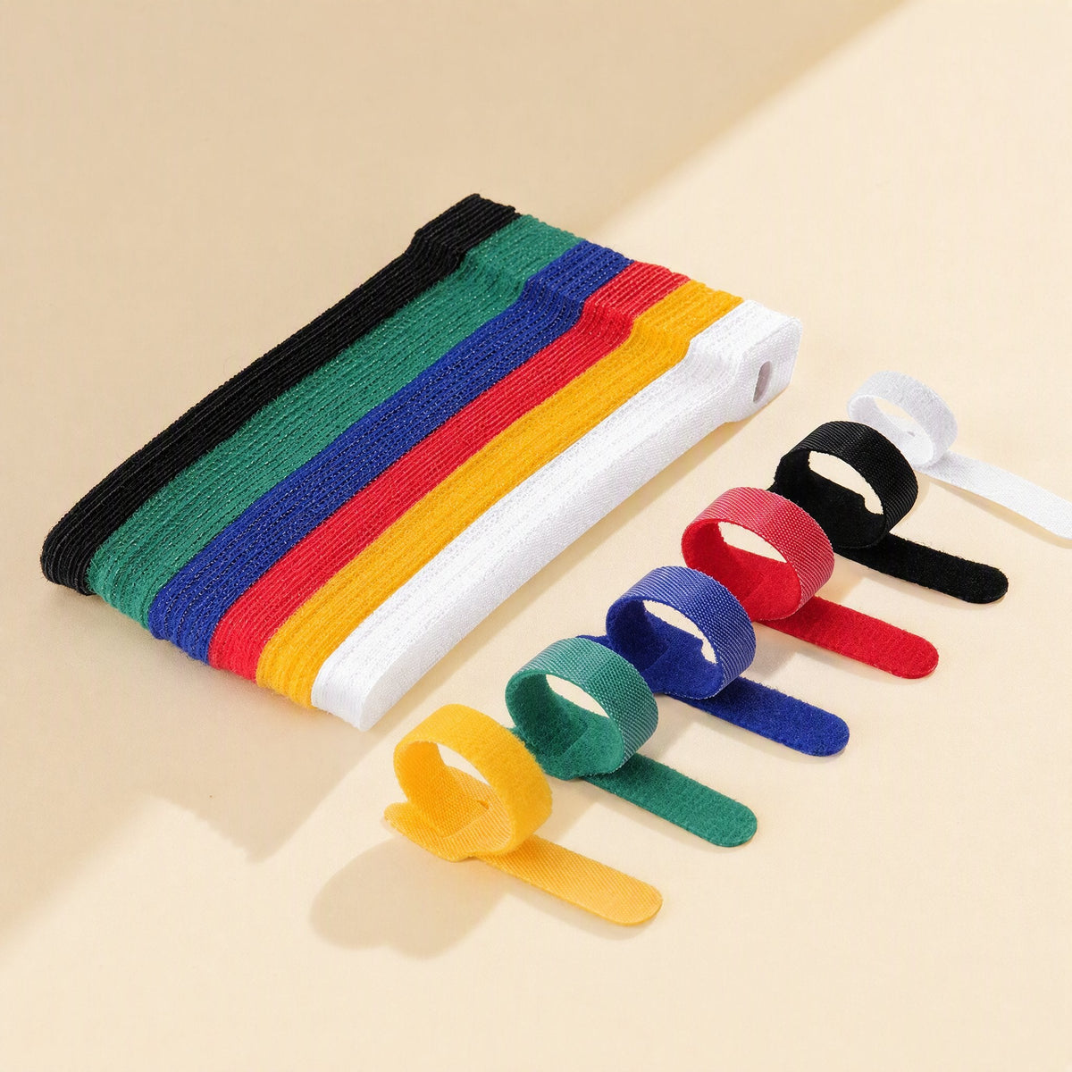 Loopmate Nylon Back-To-Back Hook-and-Loop Cable Tie stack in six colours beside looped ties on beige