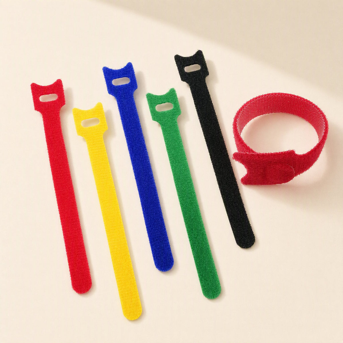 Loopmate – Red, yellow, blue, green and black cable ties lying flat, with a red tie fastened into a loop at right