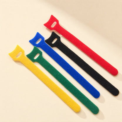 Loopmate – Five cable ties in yellow, green, blue, black and red fanned out diagonally on a beige surface