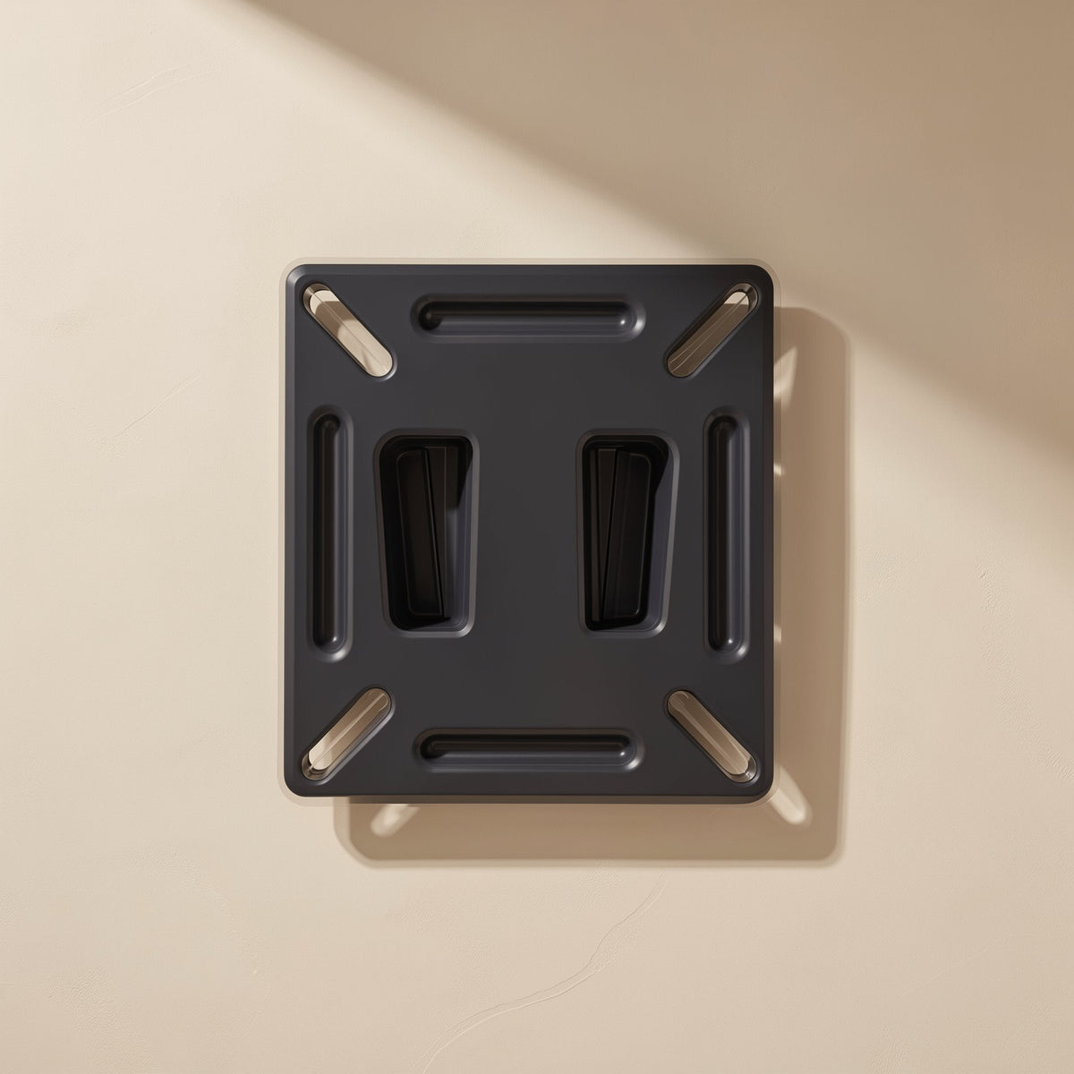 Wallpivot Iron Monitor Wall Mount – front view of the black bracket mounted flat on a beige wall with soft diagonal shadow