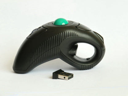 Orbitgrip – Side view of the black grip mouse with green trackball, finger loop and ridged side, USB receiver in front