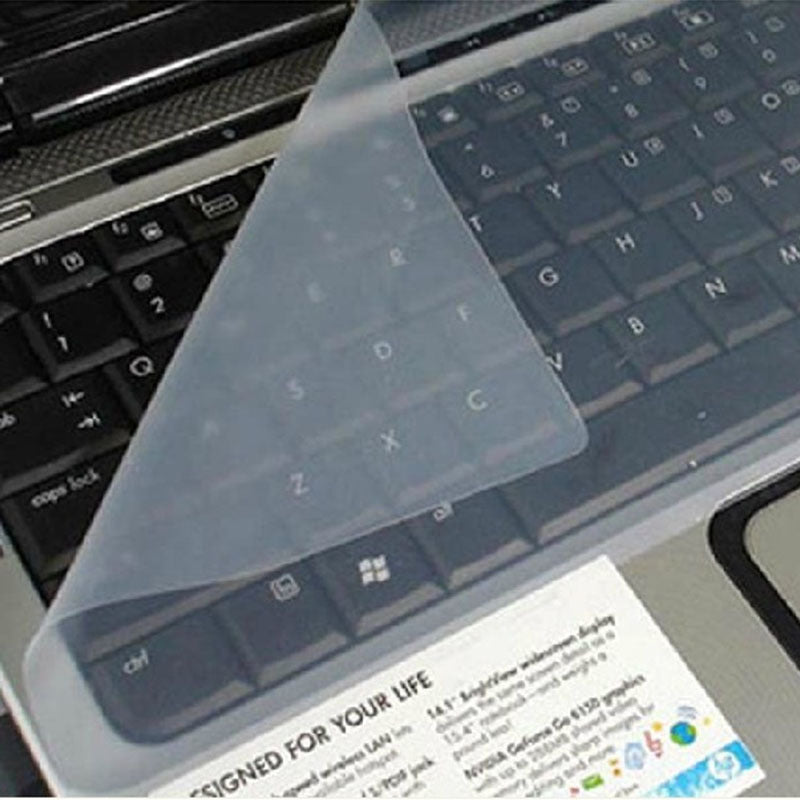 Keyfilm – Transparent silicone keyboard cover lifted at one corner over a black laptop keyboard with a sticker below